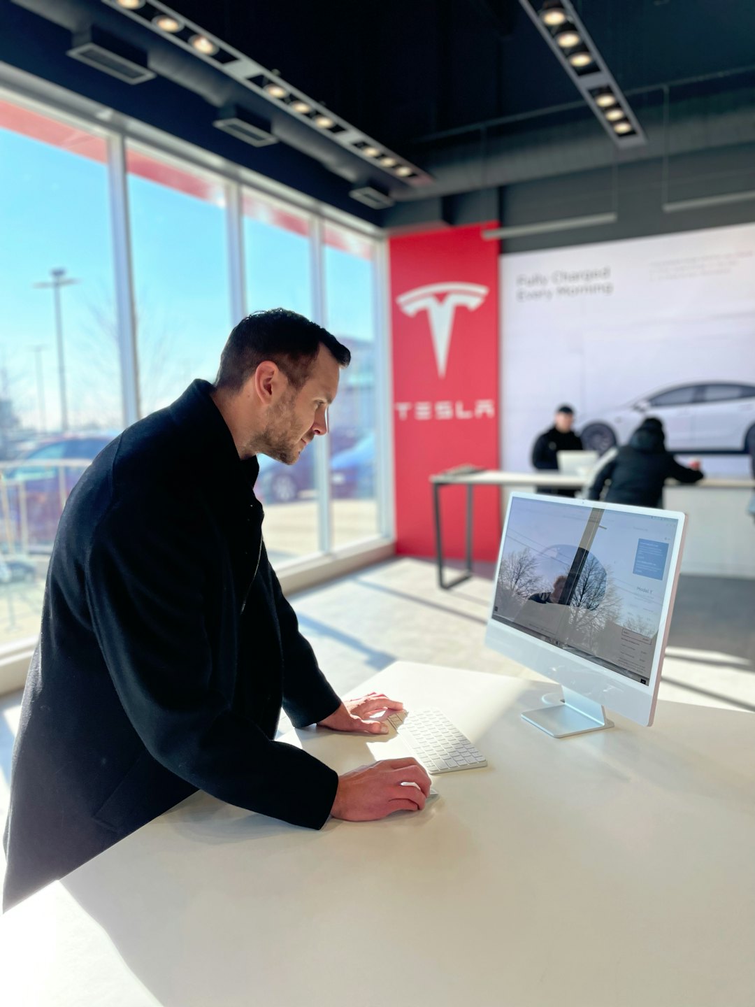 Uomo che usa un computer alla scrivania in un moderno showroom d'auto.