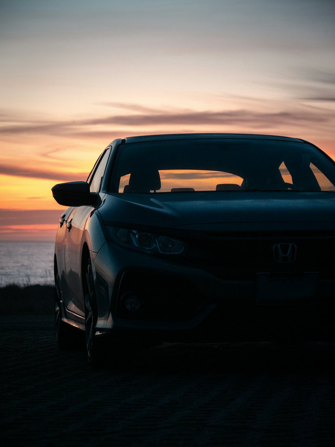 Sedan moderna parcheggiata con vista sull'oceano al tramonto.