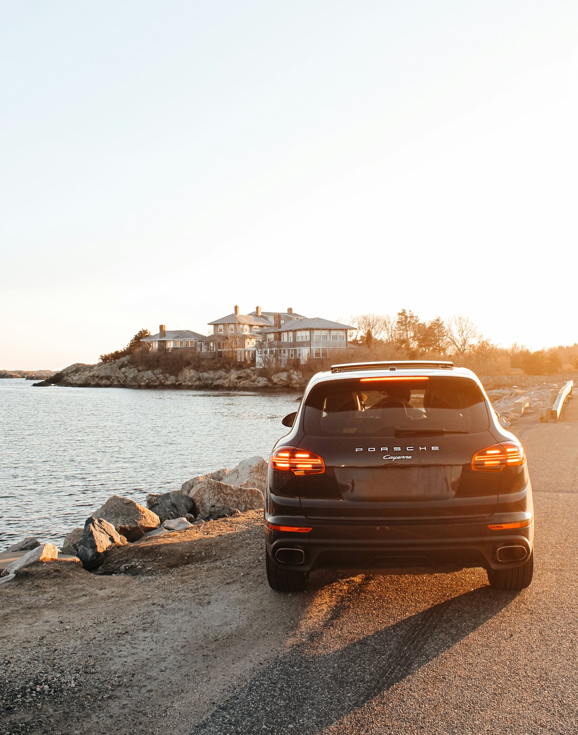 SUV di lusso parcheggiato vicino a una costa rocciosa al tramonto.