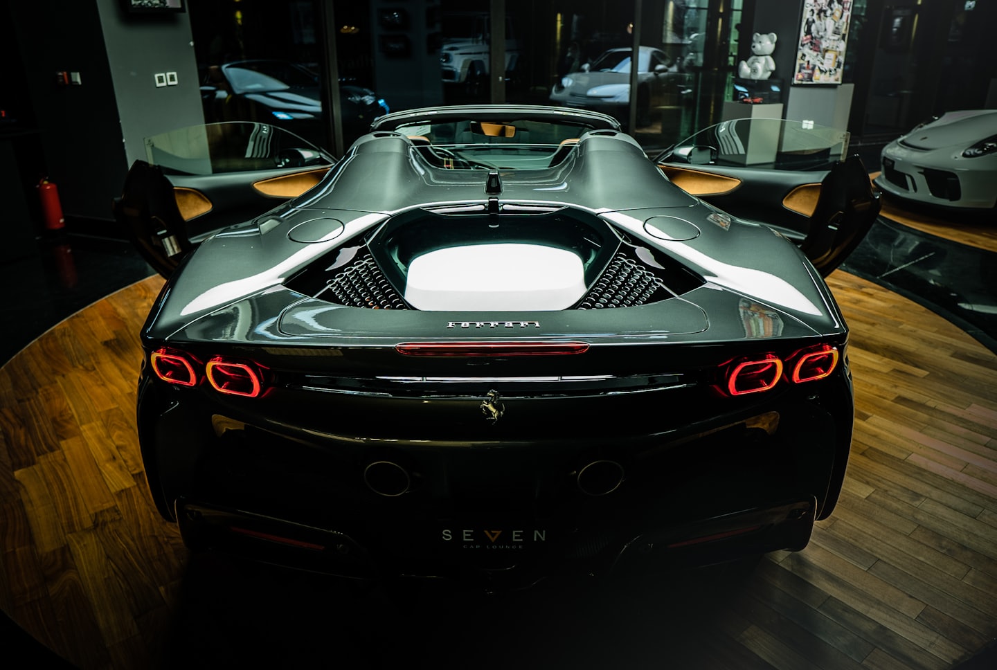 Vettura sportiva grigio scuro con portiere aperte in uno showroom.